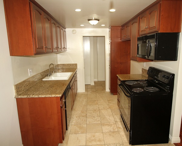 Kitchen with custom cherry wood cabinets, granite counters and Travertine tile