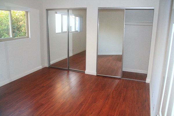 Large Bedroom with Hardwood Laminate Floors and Large Mirrored Closets