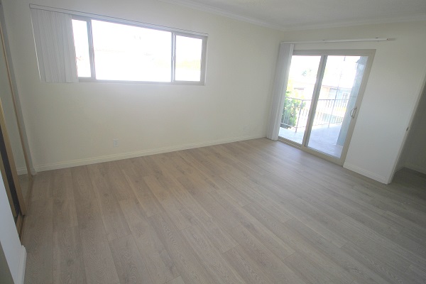 Upper bedroom with hardwood floor and mirrired closets leading to balcony with ocean views